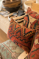 Textured surface of a vintage rug fragment pillow with geometric rust, navy, and gold pattern.