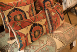 Aged hand-knotted Antique Bijar rug fragment pillows with terracotta, indigo, and cream geometric patterns.