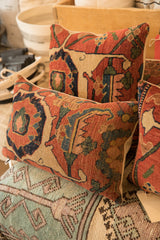 Angled view of an antique Persian Bijar pillow, showing hand-knotted texture and bold motifs.