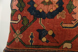Textured antique Bijar rug fragment pillow, showing geometric floral motifs in brick red, indigo, olive, and gold.