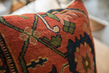 Textured hand-knotted antique Persian Bijar rug pillow with rust, green, and navy botanical motifs.