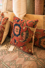 Side view of antique Bijar rug fragment pillow, showing patterned front, beige backing, and tag.