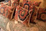 Varied antique Bijar rug fragment pillows display rich rust, sapphire, and cream tribal patterns.