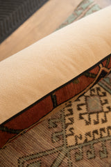 Beige pillow backing, black piping, and antique Bijar geometric rug fragment edge.