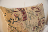 Angled view of vintage rug fragment pillow with time-softened Persian mythological motifs.