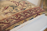 Angled detail of the hand-knotted antique Kerman pillow, with faded red and blue mythological motifs.