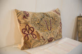 Angled view of antique Persian Kerman rug fragment pillow, mythological motifs in muted tones.