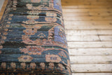 Textured weave of the vintage Turkish rug fragment on the bench showing charcoal, teal, and raspberry hues.