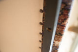 Close-up of the rug bench's finished underside with cotton canvas and brass tacks.