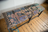 Angled view of a long bench featuring reclaimed vintage Turkish rug upholstery in charcoal and lavender.