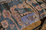Angled view of the Turkish rug bench's upholstery showing worn texture and knot-heads.