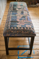 Long perspective view of the reclaimed rug bench with its dark ebony-stained wood legs.