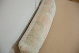 Textured side view of vintage lumbar pillow, showing faded Oushak rug remnant.