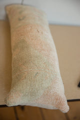 Muted pastel hues and distressed texture of the vintage lumbar pillow.