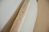 Distressed vintage rug fragment pillow edge, showcasing peach-green pile texture and neutral fabric.