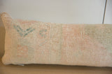 Distressed hand-knotted pile texture of the vintage lumbar pillow, showing faded peach and teal.