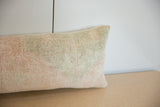 Visible hand-knotted texture on the faded pastel peach and sage vintage pillow.