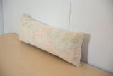 Angled vintage lumbar pillow with faded peach and green hand-knotted texture.
