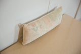 Distressed vintage Oushak rug remnant texture on a lumbar pillow end.
