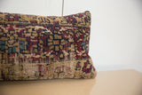 Side profile of a vintage rug pillow showing its worn, low-pile texture and pattern.