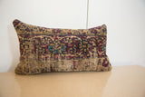 The textured, low-pile surface of a vintage rug fragment pillow with muted geometric patterns.