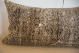 Distressed hand-knotted vintage rug fragment pillow with textured brown and gray weave.