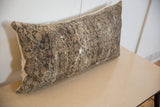 Distressed vintage rug fragment pillow with faded pattern and textured low pile.