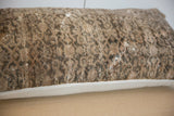 Side view of distressed Malayer rug fragment pillow, showing worn texture and visible foundation.