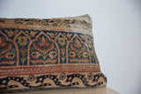 Aged blue, red, and tan curvilinear motifs on vintage Kerman rug fragment pillow's edge.