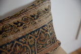 Faded blue and tan motifs on a hand-knotted Kerman rug fragment pillow.