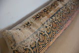Textured vintage Kerman rug fragment pillow with faded blue and gold curvilinear patterns.