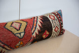 Angled view of a vintage rug lumbar pillow with a textured, hand-knotted geometric design.