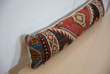 Angled profile of a vintage rug lumbar pillow with a patterned blue and orange end cap.