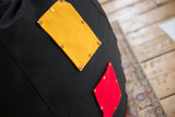 Riveted yellow and red swappable cotton pockets on the black hemp bean bag.