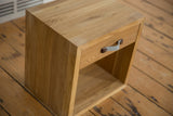 Angled view of the solid oak nightstand showcasing the wood grain and grey felt handle.