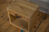 Three-quarter view of the oak nightstand, highlighting the wood grain top and felt handle.