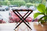 Angled view of rug fragment footstool, hand-knotted top with ornate red and orange pattern.
