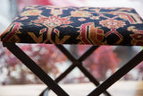 Angled view of hand-knotted rug fragment footstool, dark blue ground, ruby red, coral pattern.
