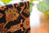 Vintage rug fragment footstool side, with hand-knotted texture and black, gold, red patterns.