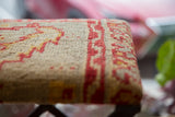 Rug Fragment Footstool top with textured neutral ground and geometric red and yellow patterns.