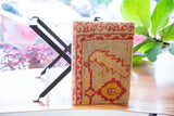 Geometric red and yellow pattern on textured vintage rug fragment footstool corner.