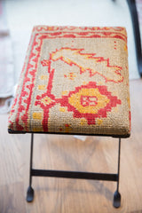 Black industrial metal base of the rug footstool on a light wood floor.