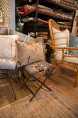Reclaimed antique Persian lumbar pillow on patterned stool with floral vinery motif.