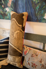 Lower end of vintage Turkish rug fragment lumbar pillow, with textured pile and pink backing.