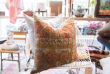 Detailed side view of antique Belouch fragment pillow, with blue piping and worn texture.