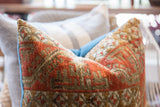 Close-up of handmade antique Belouch pillow showing terracotta geometric pattern and blue piping.