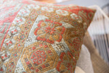 Antique Belouch rug pillow detail, featuring distressed geometric patterns in rust and blue.