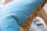 Hand-knotted antique Belouch rug fragment edge with textured blue pillow backing.