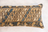 Textured close-up of vintage Caucasian rug fragment pillow with geometric beige, blue, brown pattern.