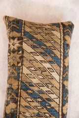 Close-up of vintage Caucasian rug lumbar pillow with geometric brown, tan, and blue patterns.
